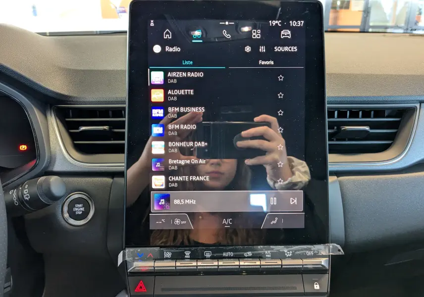 Écran tactile central vertical du tableau de bord du Renault Captur 2025 avec interface radio et commandes climatisation.