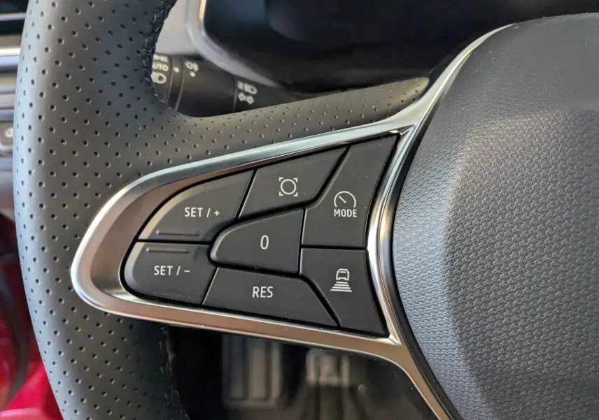 Gros plan sur les commandes du volant en cuir perforé du Renault Captur E-Tech rouge flamme avec finition noire.