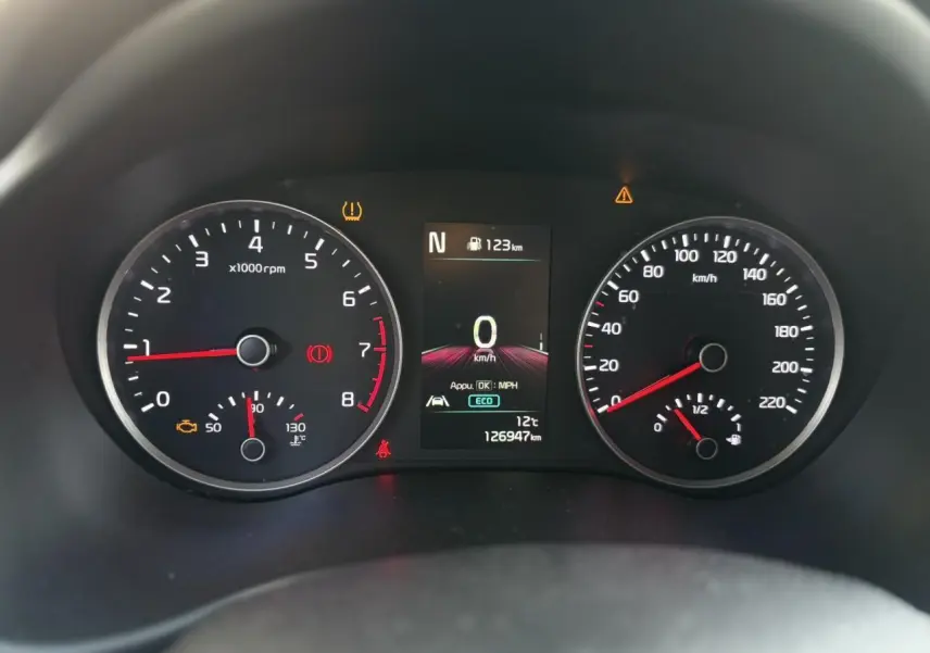 Vue rapprochée du volant noir perforé avec commandes multifonctions du KIA Stonic 2020, tableau de bord flou en arrière-plan.