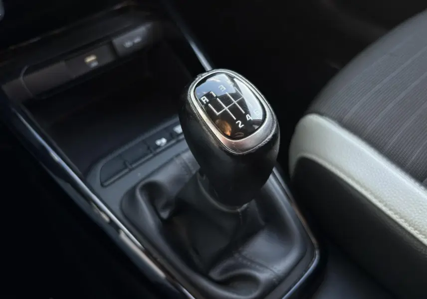 Vue rapprochée de la console centrale noire du Kia Stonic rouge, avec commandes climatisation et ports USB visibles.