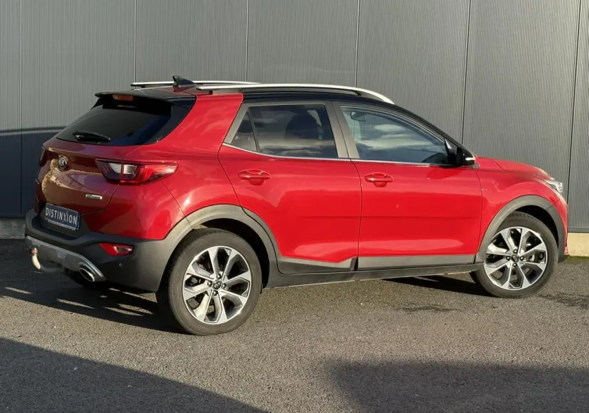 Vue 3/4 arrière droite d'un Kia Stonic rouge métallisé avec attelage et jantes alliage 17 pouces.