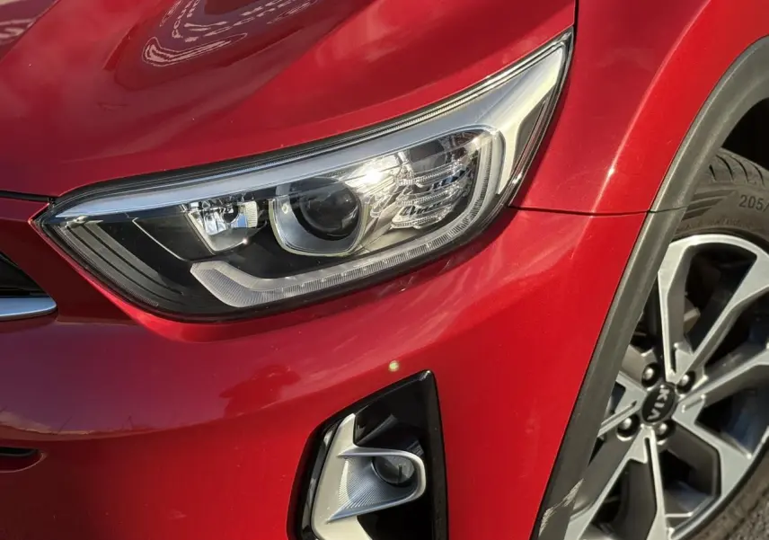 Gros plan sur l'avant droit rouge métallisé du KIA STONIC 2020, mettant en valeur le phare et le projecteur antibrouillard.
