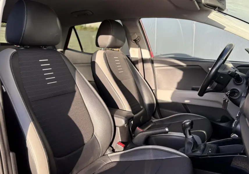 Vue intérieure des sièges avant noirs et gris du KIA Stonic rouge, avec levier de vitesse manuel visible.
