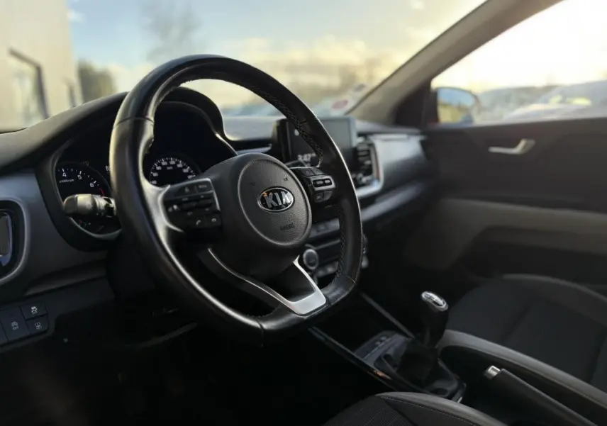 Vue intérieure frontale du tableau de bord et volant KIA Stonic avec écran tactile et boîte manuelle.