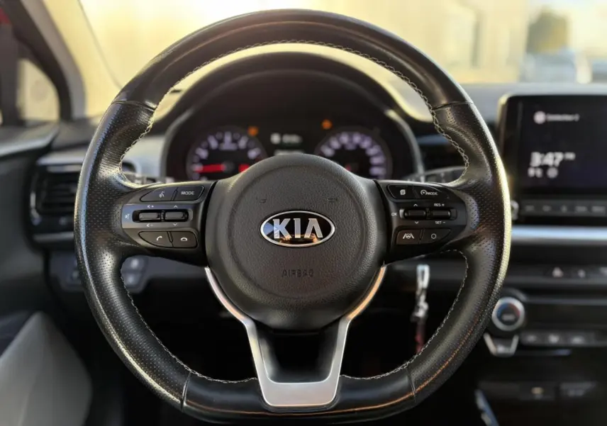 Vue intérieure côté conducteur du tableau de bord et volant KIA Stonic avec écran tactile et levier de vitesses manuel.