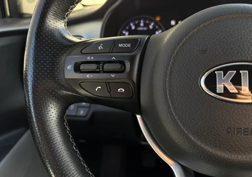 Gros plan sur la commande des vitres électriques côté conducteur du Kia Stonic rouge, avec réglage des rétroviseurs.