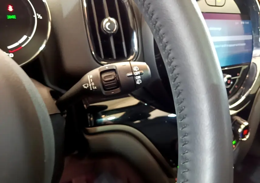 Gros plan sur le volant cuir noir et la commande d’essuie-glace du MINI Countryman Cooper SE hybride 2023.