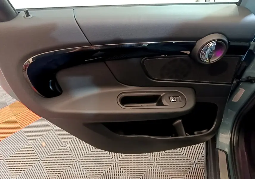 Vue rapprochée de la porte côté gauche verte du MINI COUNTRYMAN Cooper SE avec poignée et haut-parleur intégrés.