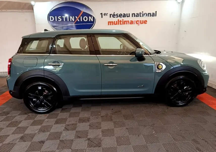 Profil côté gauche d'un MINI Countryman hybride rechargeable vert avec toit blanc et jantes noires brillantes.