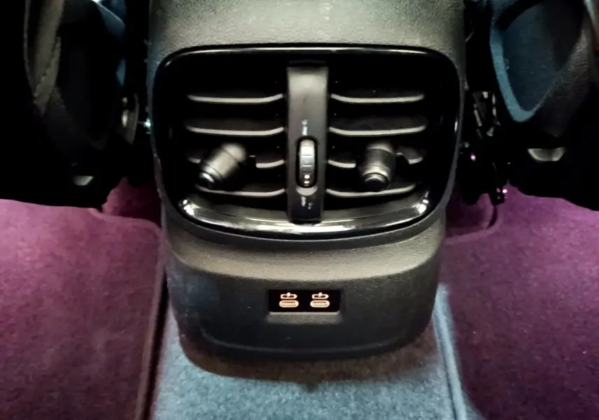 Gros plan sur la sortie d'air arrière noire et les commandes de chauffage des sièges dans un MINI Countryman vert 2023.