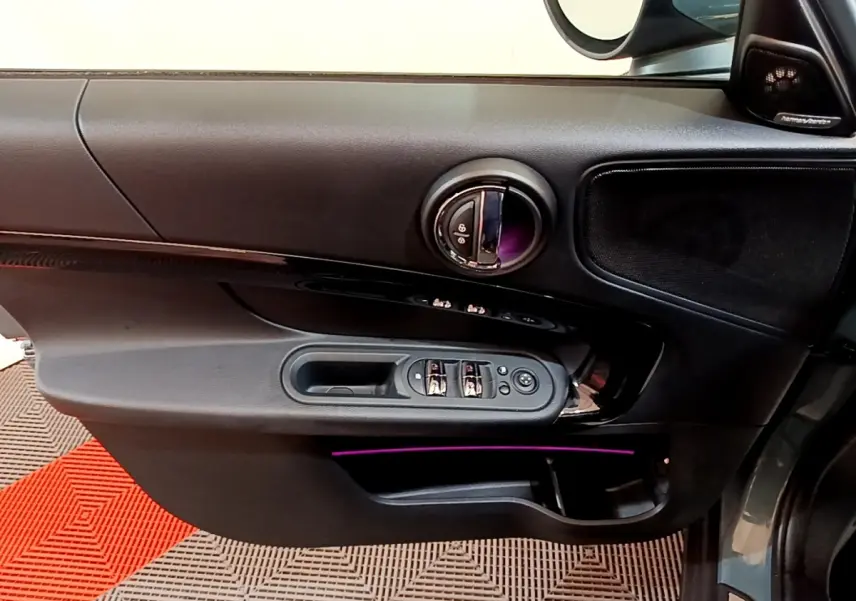 Porte côté conducteur noire du MINI Countryman Cooper SE 2023 avec éclairage d'ambiance violet et commandes électriques.
