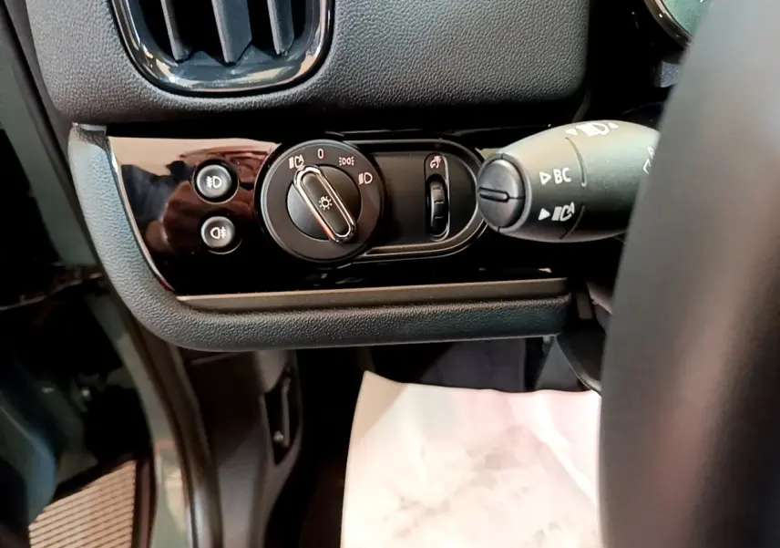 Gros plan sur les commandes d'éclairage côté gauche du tableau de bord noir du MINI Countryman vert 2023 hybride rechargeable