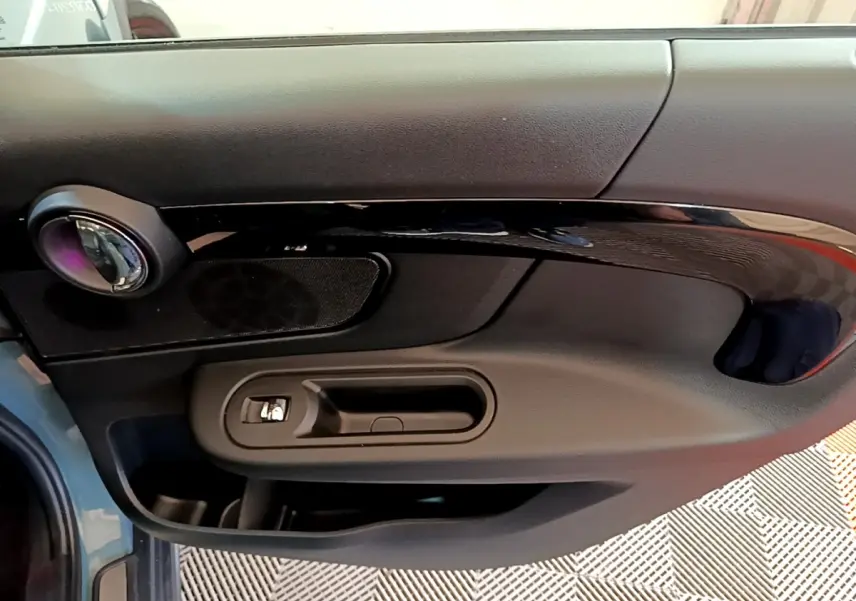 Vue rapprochée de la porte côté gauche d'une MINI Countryman hybride verte, avec poignée et haut-parleur intégrés.
