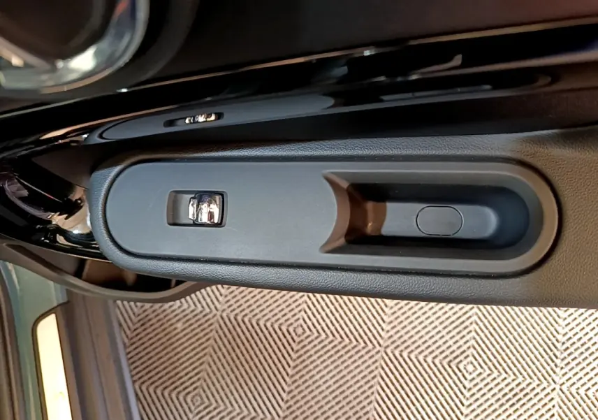 Poignée intérieure de porte côté gauche du MINI Countryman vert, avec commande de verrouillage visible.