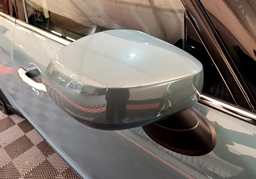 Rétroviseur côté gauche vert métallisé du MINI COUNTRYMAN Cooper SE 2023 avec carrosserie et poignée visibles.