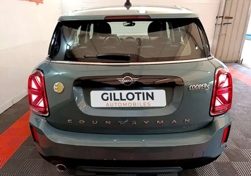 Vue arrière d'une MINI Countryman Cooper SE verte avec logo électrique et feux arrière LED allumés.