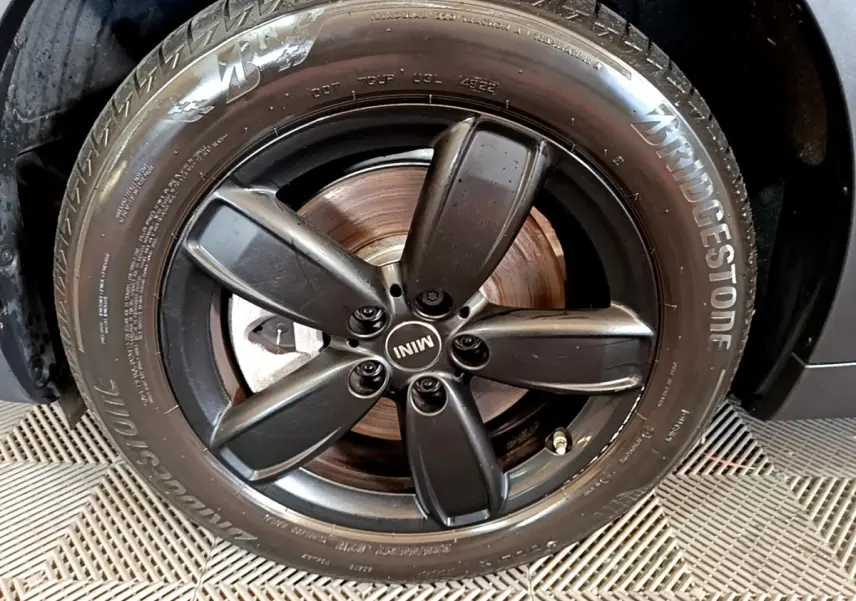 Gros plan sur la jante noire à cinq branches du MINI Countryman vert 2023 avec pneu Bridgestone visible.