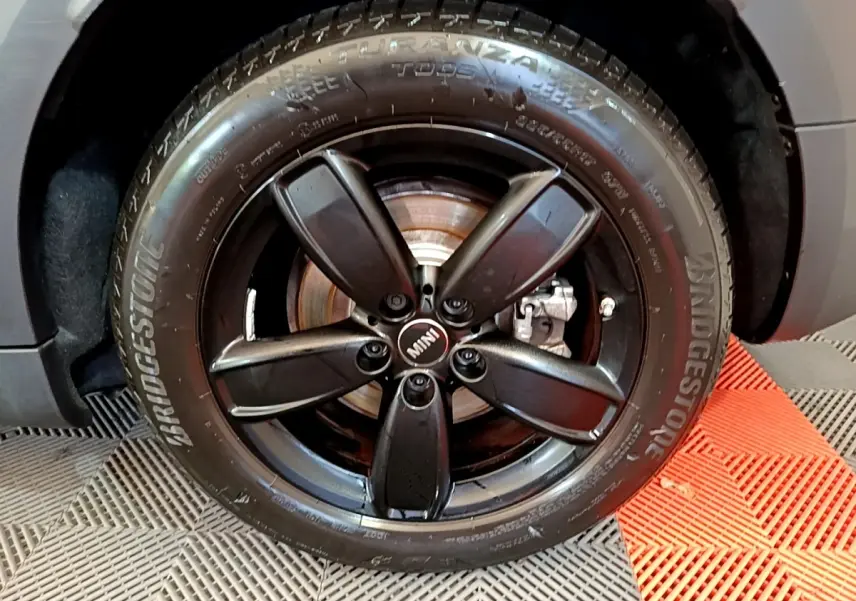 Gros plan sur la roue avant droite du MINI Countryman vert avec jante noire à cinq branches et pneu Bridgestone.