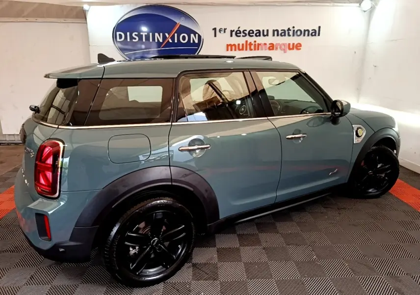 Vue 3/4 arrière droite d'une MINI Countryman hybride rechargeable verte avec jantes noires et toit noir.