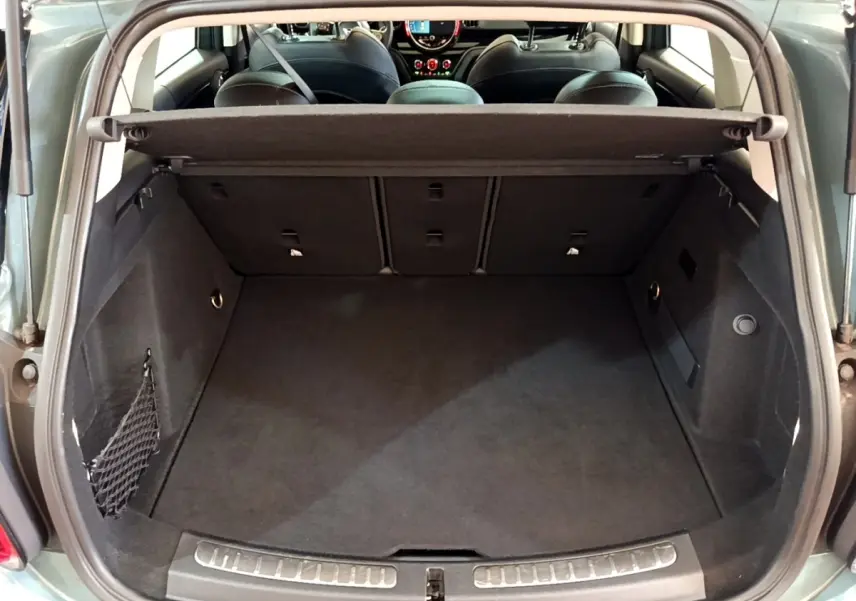 Coffre ouvert vu de l'arrière d'une MINI Countryman Cooper SE vert avec banquette arrière rabattable et cache-bagages.