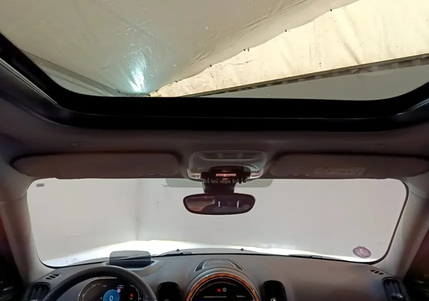Vue intérieure avant du MINI Countryman Cooper SE avec toit ouvrant panoramique et tableau de bord moderne.