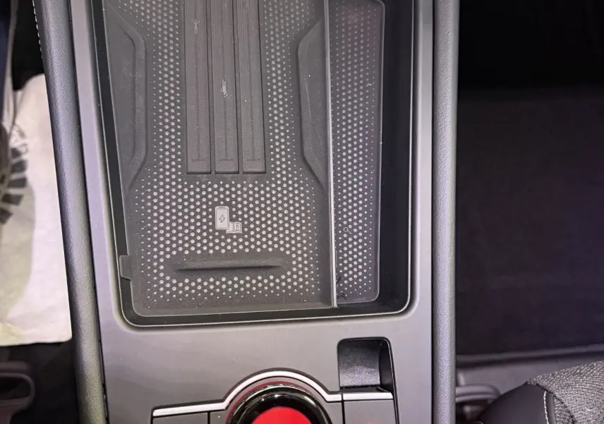 Vue rapprochée de la console centrale noire du Volkswagen T-Roc 2026, avec bouton rotatif et zone de recharge sans fil.
