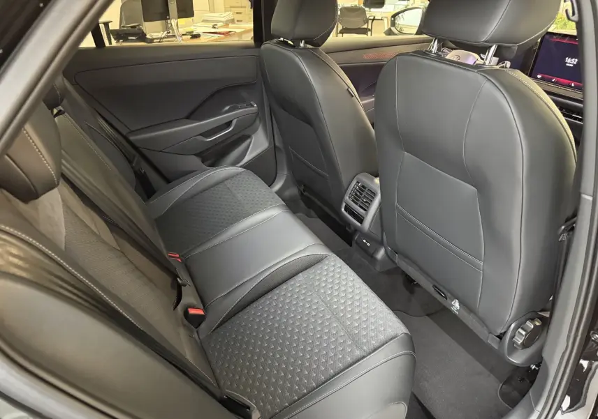 Vue intérieure arrière du Volkswagen T-Roc noir intense, montrant les sièges arrière en cuir et tissu avec aérateurs centraux.