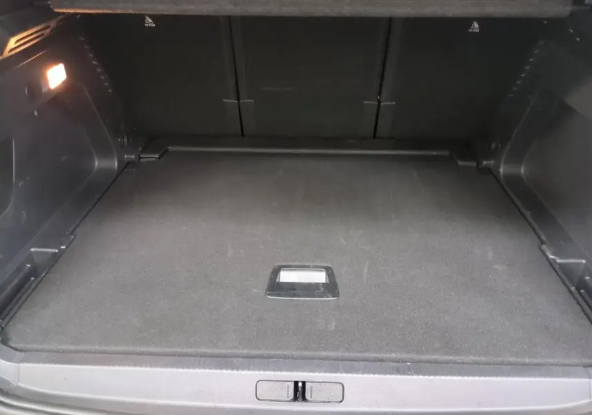 Coffre ouvert vu de l'arrière d'un Citroën C5 Aircross Hybrid gris Platinium avec hayon électrique et éclairage intérieur.