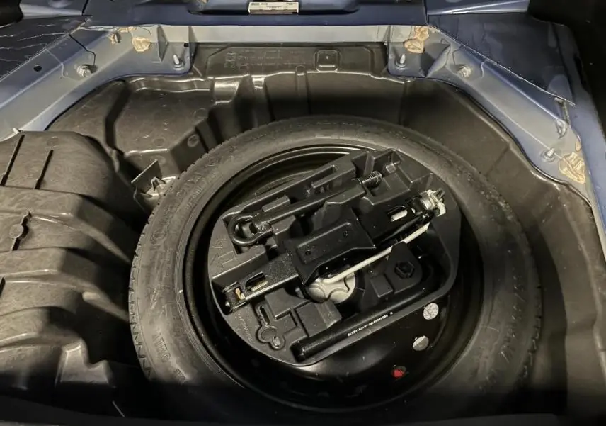 Vue plongeante sur la roue de secours galette noire dans le coffre bleu de la Renault Mégane GT 2016.