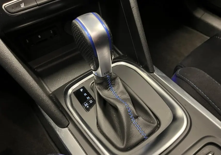 Gros plan sur le levier de vitesses automatique noir avec surpiqûres bleues de la Renault Mégane GT 2016.