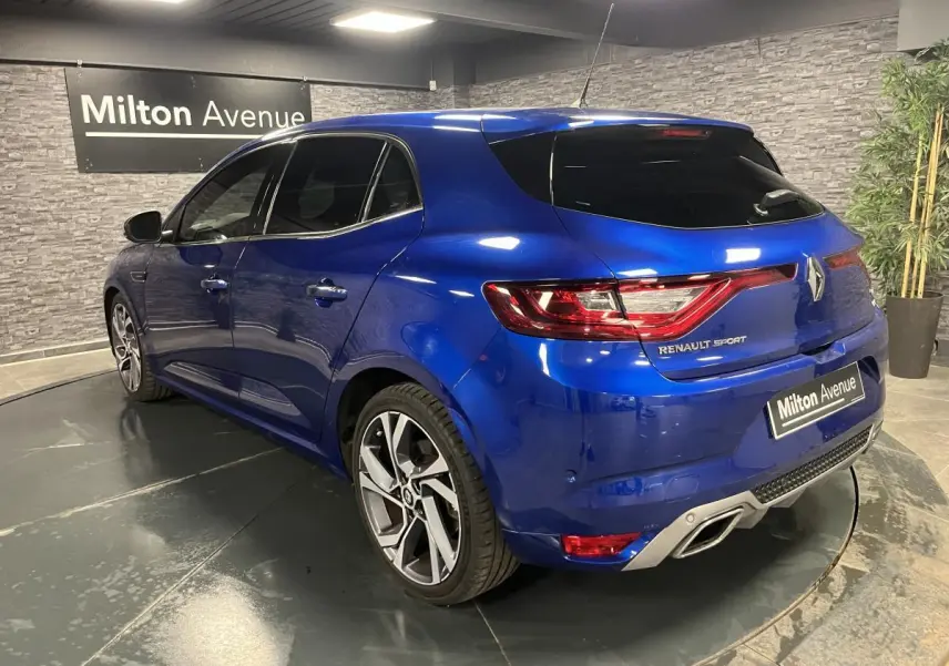 Vue 3/4 arrière droite d'une Renault Mégane GT bleu Iron avec jantes alliage 18 pouces et double sortie d'échappement intégrée.