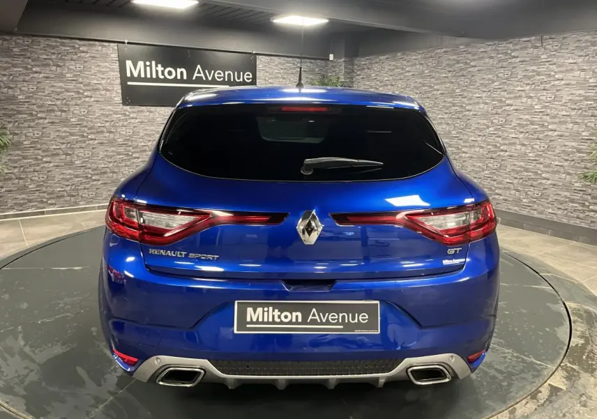 Vue arrière d'une Renault Mégane GT bleu Iron avec double sortie d'échappement et logo Renault Sport visible.