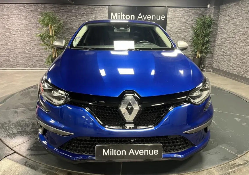 Vue avant d'une Renault Mégane GT bleu Iron avec calandre noire nid d'abeilles et logo Renault chromé.
