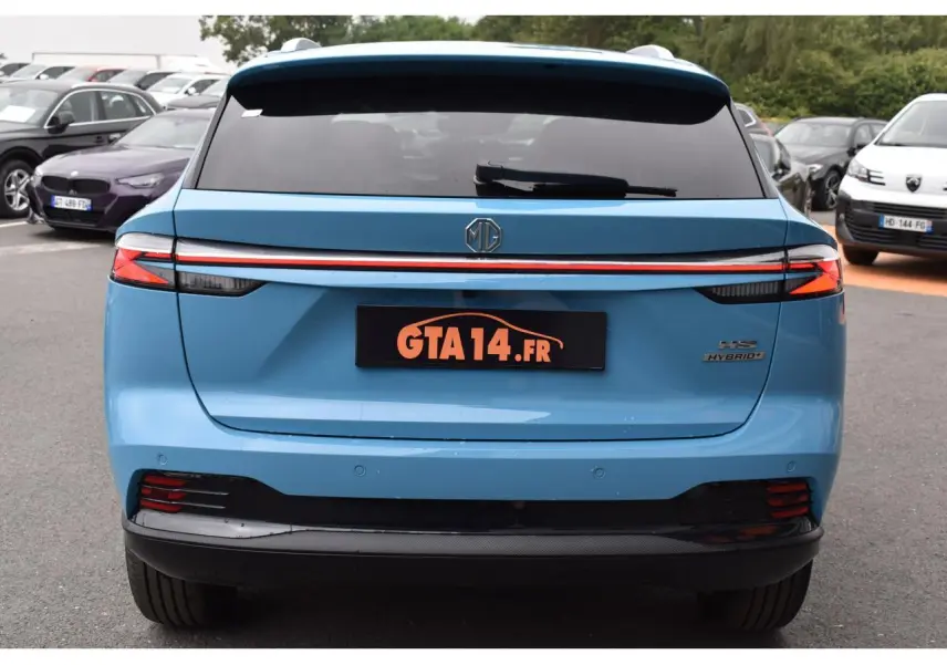 Vue arrière d'un MG Motor EHS bleu 2026 avec feux arrière reliés par une bande lumineuse rouge distinctive.