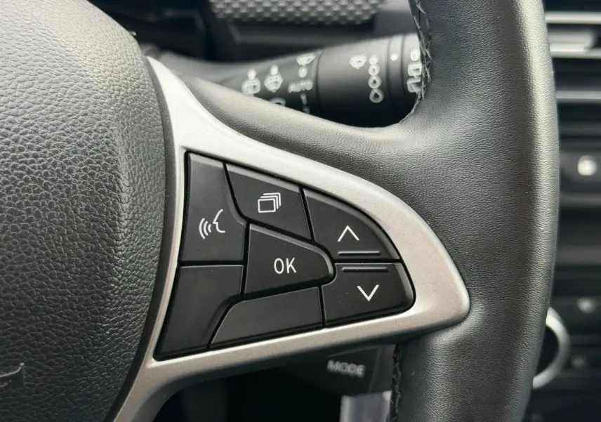 Gros plan sur les commandes multifonctions noires et argentées du volant du Dacia Jogger 2025.