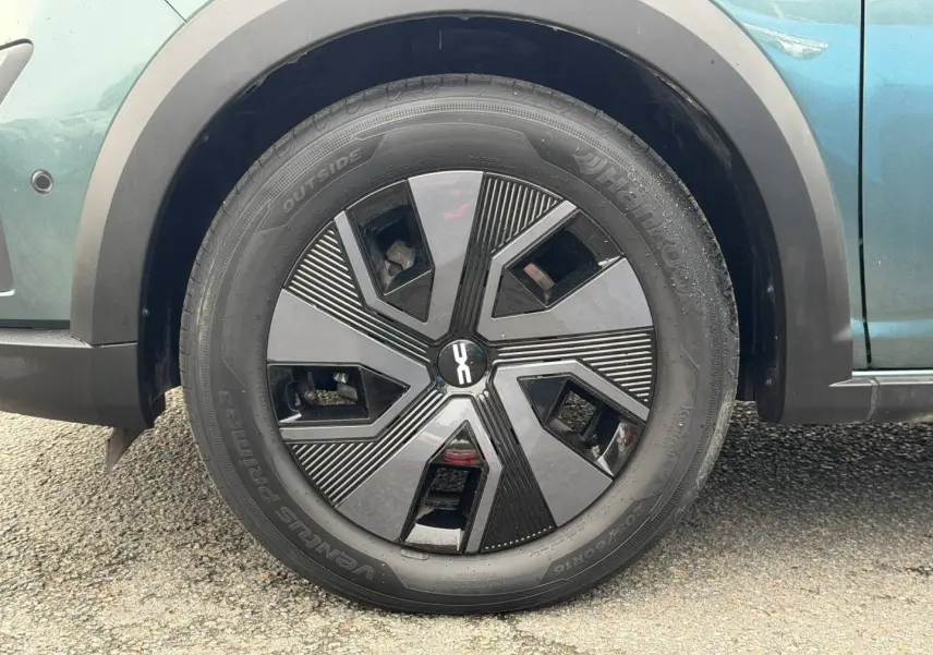 Gros plan sur la roue avant gauche du Dacia Jogger vert cèdre métallisé avec jante noire au design géométrique.