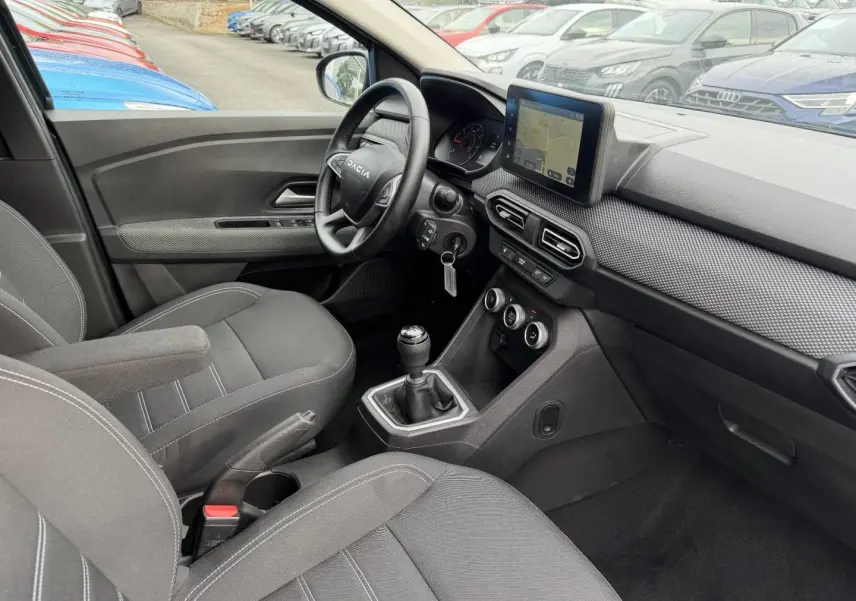 Intérieur de la Dacia Jogger 2025 vu côté conducteur, tableau de bord avec écran tactile et volant multifonction.