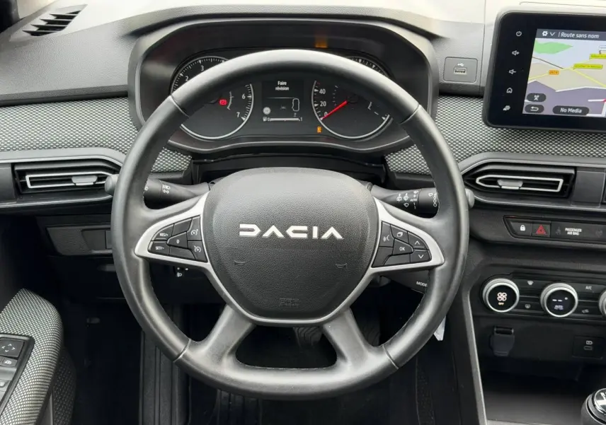 Vue rapprochée du volant et tableau de bord du Dacia Jogger 2025, avec écran tactile et commandes au volant visibles.