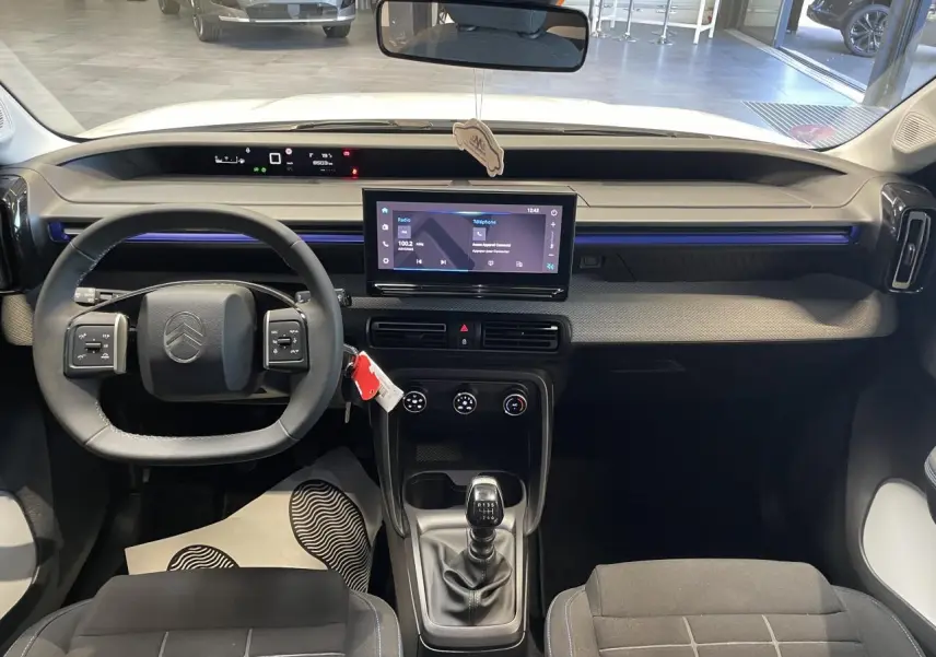 Vue intérieure avant de la Citroën C3 blanche 2025, tableau de bord avec écran tactile et volant multifonctions.