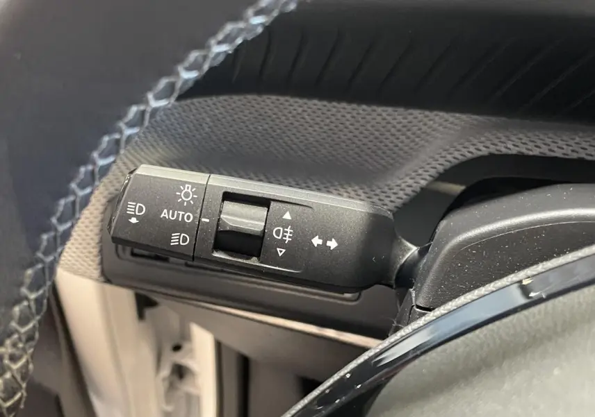 Gros plan sur la commande des feux et clignotants à gauche du volant dans l’habitacle d’une Citroën C3 blanche 2025.