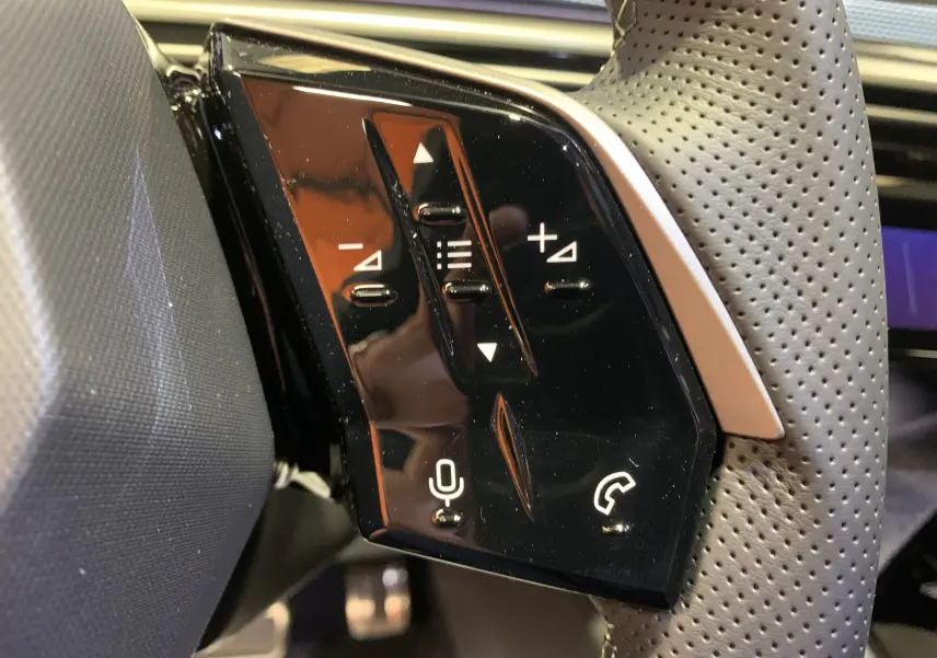 Gros plan sur les commandes tactiles noires à gauche du volant perforé du Peugeot 3008 III GT Hybrid 136 e-DSC6 2025.