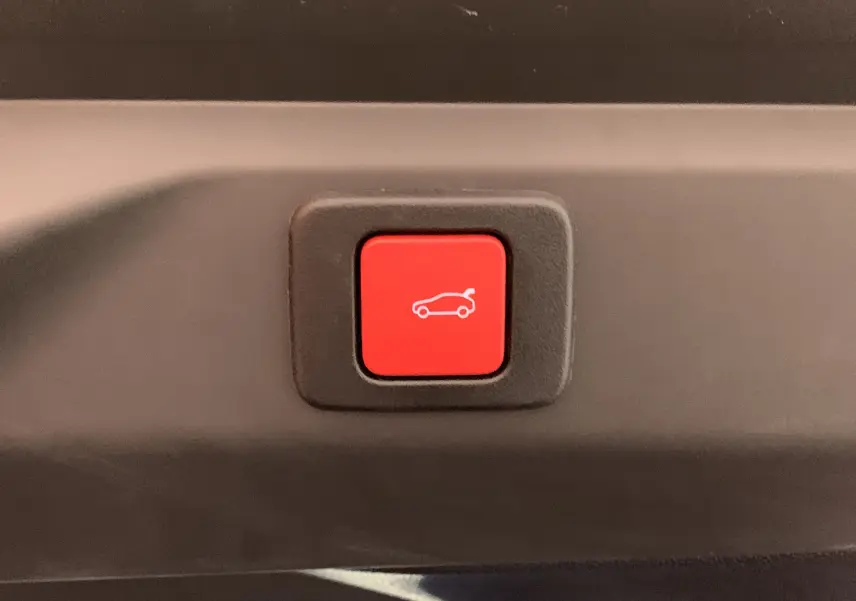 Bouton rouge de fermeture électrique du hayon sur Peugeot 3008 III GT Hybrid 136 e-DSC6 gris Artense, vue rapprochée intérieure.