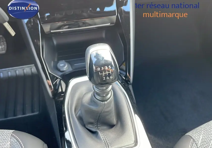 Le levier de vitesses manuel noir de la Peugeot 2008 2025, avec console brillante et sièges tissu gris.