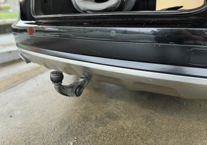 Gros plan sur l'attelage de remorque à l'arrière d'une Audi A6 Avant Allroad noire, avec pare-chocs argenté visible.
