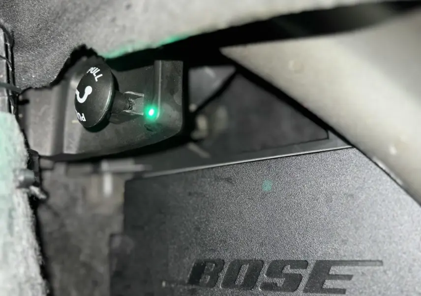Gros plan sur l'amplificateur Bose installé dans l'Audi A6 Avant Allroad noire, vue intérieure sous le tableau de bord.