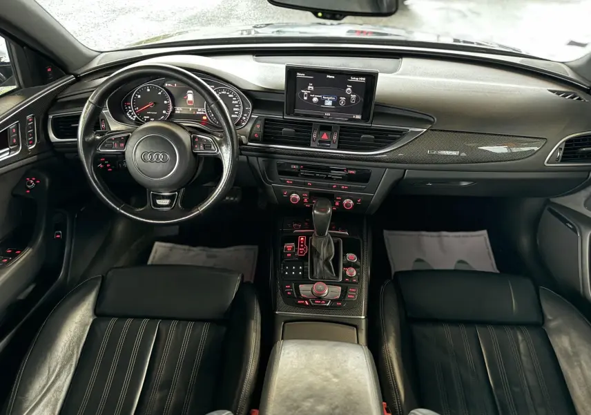 Vue intérieure avant de l'Audi A6 Avant Allroad 2016 noire, mettant en valeur le tableau de bord et la console centrale en cuir noir.