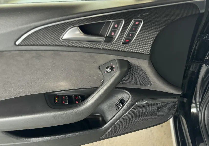 Vue rapprochée de la porte avant gauche noire de l'Audi A6 Allroad 2016 avec commandes électriques et finition carbone.