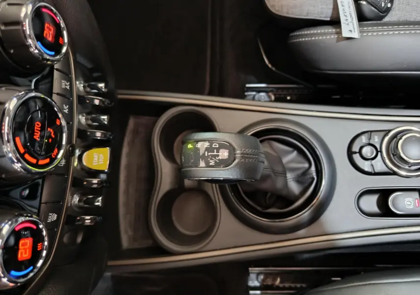 Vue plongeante sur la console centrale noire du MINI Countryman Cooper SE avec levier de vitesses automatique et commandes climatisation.