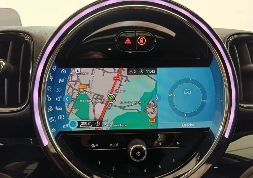 Écran tactile central du tableau de bord MINI Countryman Cooper SE blanc, affichant la navigation avec anneau lumineux violet.