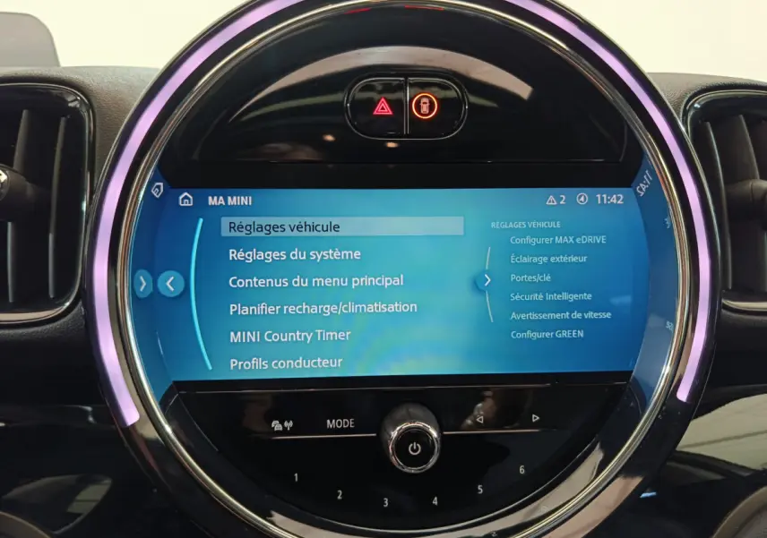 Écran tactile central circulaire allumé du tableau de bord du MINI Countryman blanc, affichant les réglages véhicule.